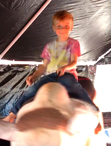 Boy riding Fu Manchu the mechanical bull under the tent