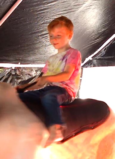 Boy riding Fu Manchu the mechanical bull under the tent