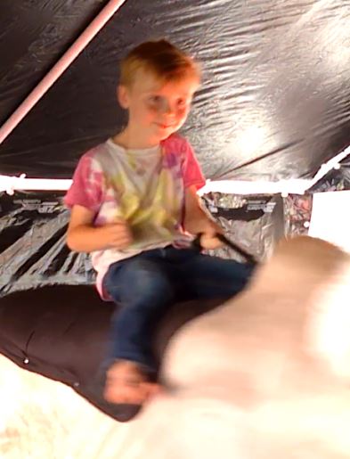 Man riding Fu Manchu the mechanical bull under the tent