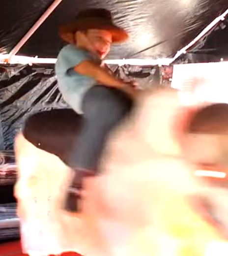 Boy riding Fu Manchu the mechanical bull under the tent